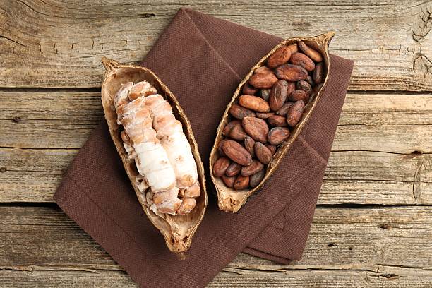 Cocoa pods with beans on wooden table, top view