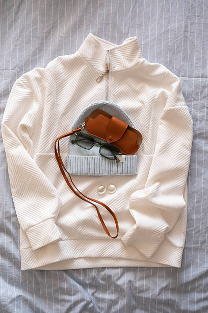 White Turtleneck Sweater And Leather Bag Staged For Weekend Trip, Soft Bed Backdrop, Neutral Palette, Sunglasses Tucked Inside Bag, Strap Coiled, Gentle Morning Light, Curated