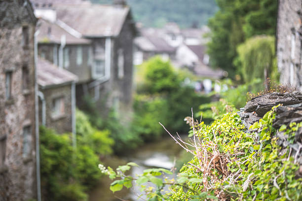A picturesque village scene with traditional stone buildings and abundant foliage surrounding a gentle stream