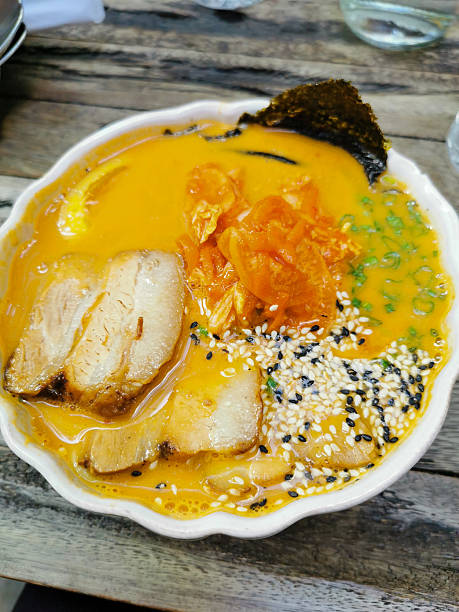 Kimchi ramen in white bowl on wooden table, closeup