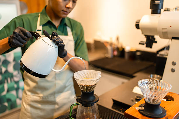 Close-up of freshly ground coffee being brewed using a pour over method with a paper filter and dripper. Hot water is poured slowly over the coffee grounds, highlighting the manual brewing process and craftsmanship of specialty coffee preparation in a café or home setting