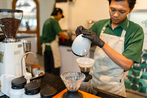 Close-up of freshly ground coffee being brewed using a pour over method with a paper filter and dripper. Hot water is poured slowly over the coffee grounds, highlighting the manual brewing process and craftsmanship of specialty coffee preparation in a café or home setting