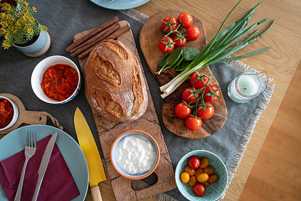 Colorful Homemade Bread Surrounded by Fresh Vegetables and Dips on the Table