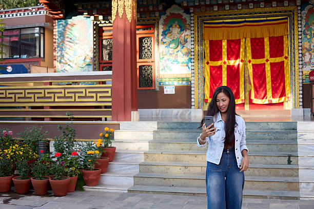 Young woman standing on temple steps holding smartphone