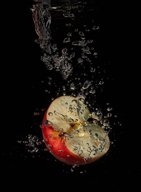 Half apple splashing in water isolated on black background