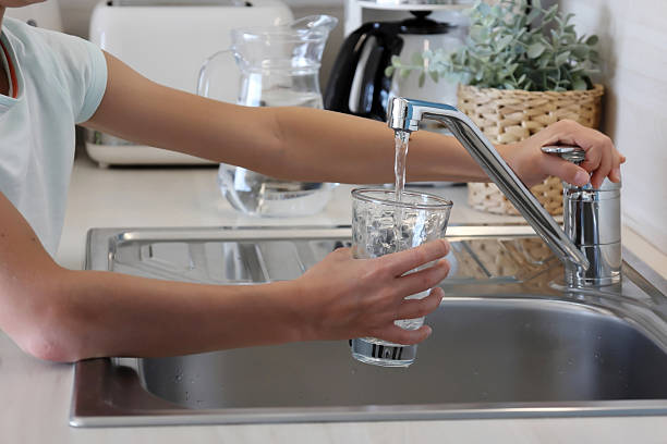 Pouring a glass of water from the kitchen faucet on a sunny day