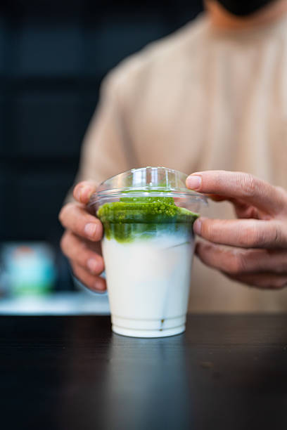A person closing a lid of iced green tea in cafe