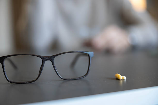 Eyeglasses resting on a table next to medicine, presenting concepts of vision care, aging eyes, and regular dosage