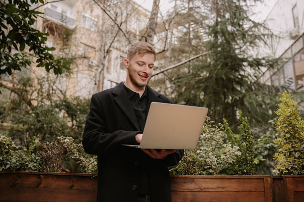 Smiling young man using laptop outdoors