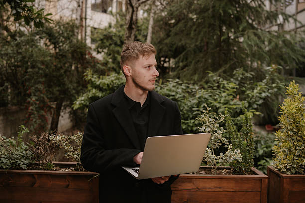 Young professional using laptop outdoors in urban garden