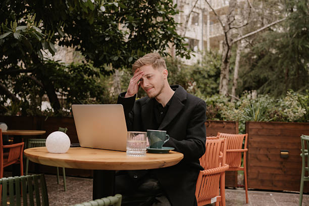 Stressed young man working on laptop in outdoor cafe