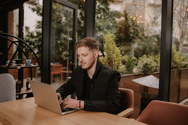 Focused young man working on laptop in modern cafe