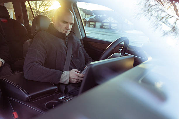 Male Driver Sitting in Driver’s Seat Using Mobile Phone