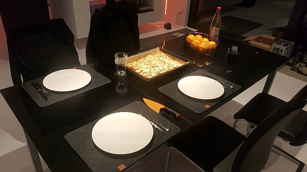 Dinner table set with freshly baked pizza, plates, and oranges ready for a meal