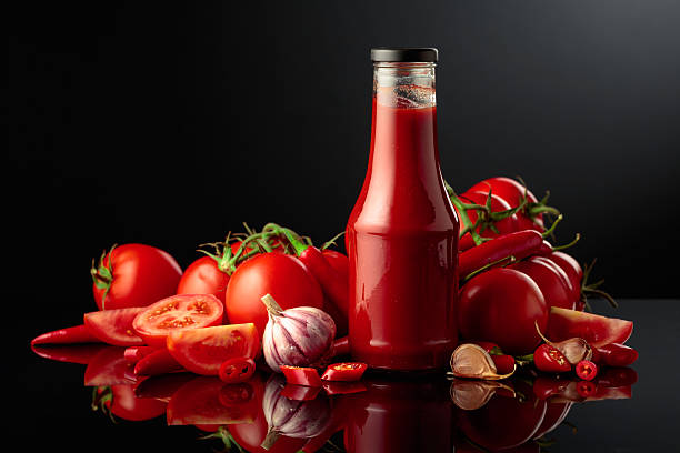 Bottle of tomato sauce with fresh tomatoes, red peppers, and garlic.