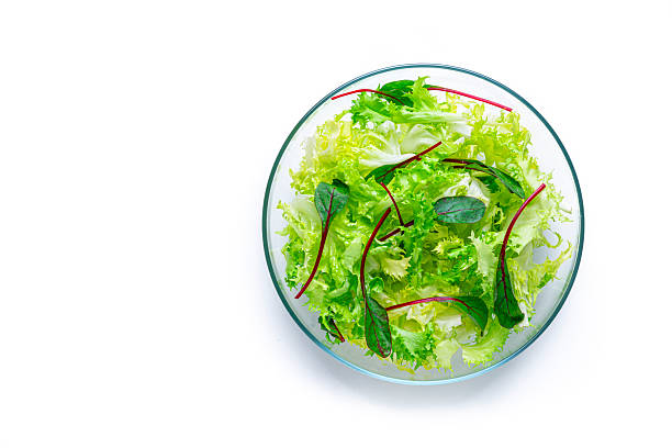Freshly prepared lettuce and spinach green salad bowl shot from above on white background. Raw food or detox dieting.