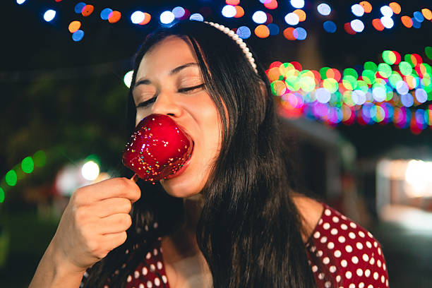 Young adult eating candy apple at fair