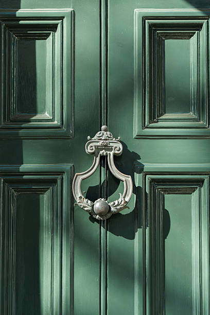 Decorative metal knocker enhancing a classic green wooden panel door in london, england