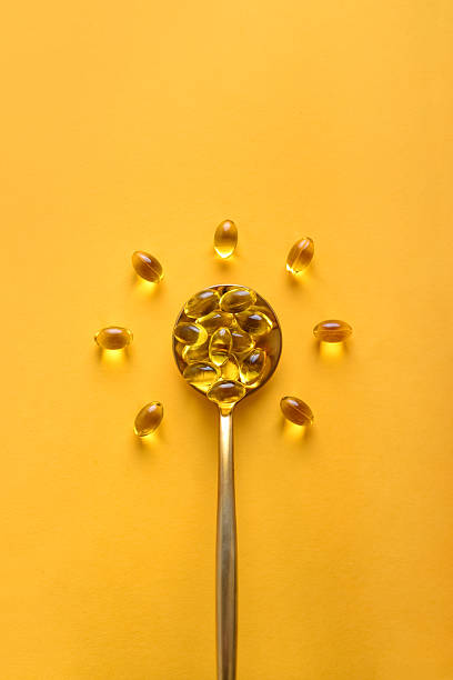 Golden spoon with soft gels vitamin D (cholecalciferol) in shape of sun