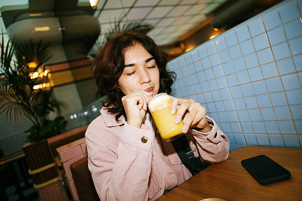 Young woman with eyes closed drinking a flavored beverage through a straw, relaxing in a modern cafe environment
