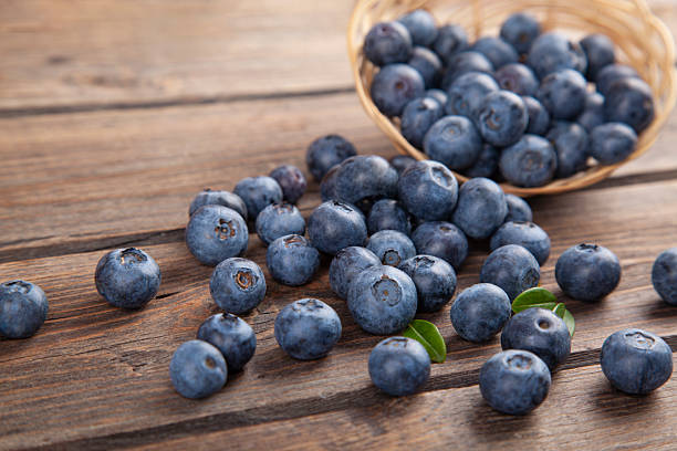Blueberries with mint leaves scattered from basket on wooden rustic table