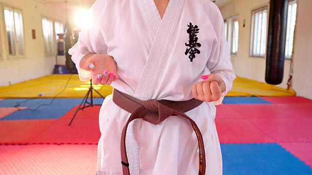 Young woman wearing a brown belt, practicing karate kata in a dojo, exuding focus and strength while mastering martial arts techniques. Girl power in combat sports. Gen Z adults enjoying offline activities concept.