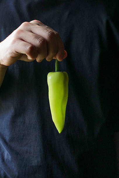 Hand holding Green pepper chili on dark background. Vegetable concept. Hot chili.