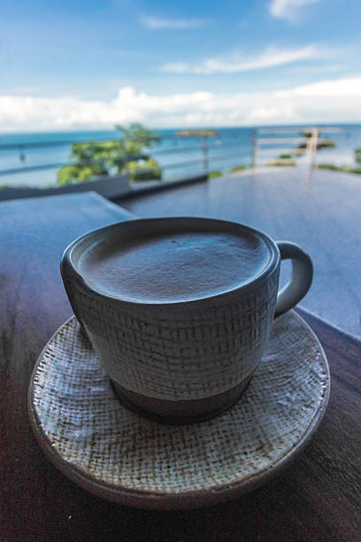 Cup of coffee on a balcony with distant beach landscape and vegetation in the background at Manuel Antonio beach located in the province of Puntarenas in Costa Rica
