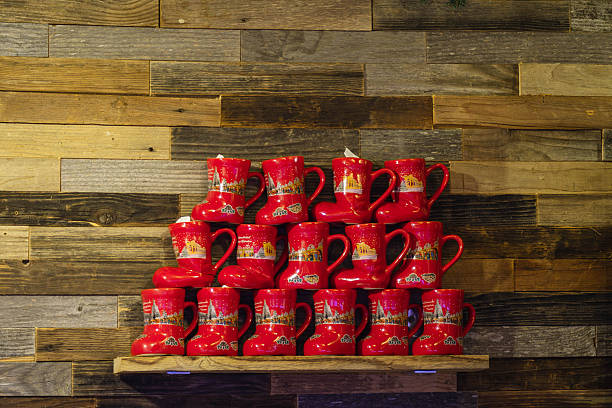 Red Ceramic Mug Display On Shelf, Stacked Pyramid Against Reclaimed Wooden Plank Wall, Patterned Glossy Glaze,