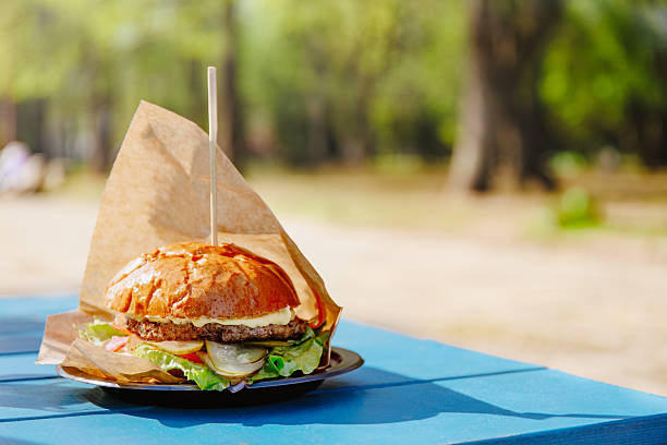 Burger Wrapped In Paper On Outdoor Table