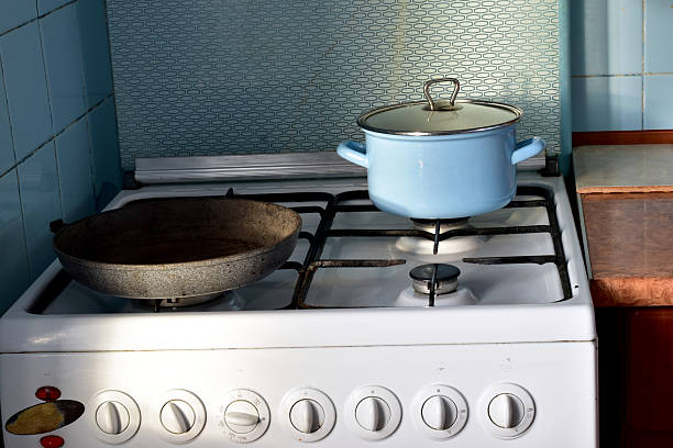 A kitchen interior in a house. A saucepan and a frying pan sit on a gas stove.