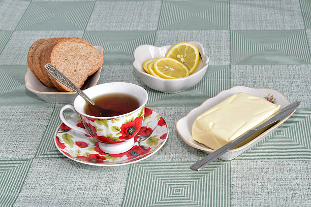 Table setting for tea drinking, including the following items: butter, bread, tea and a knife.
