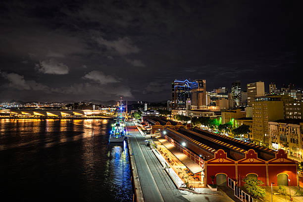 Night view of Rio de Janeiro waterfront with illuminated buildings, reflections on the water and urban architecture creating a lively cityscape.