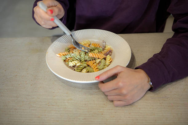 Hands Holding a Bowl of Colorful Fusilli Pasta with Fork