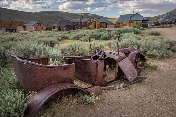 Rusted car and abandoned houses surrounded by sagebrush at Bodie State Historic Park, California