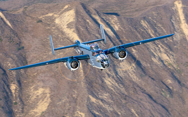 WWII era bomber (B-25 Mitchell)  flying over South California hills