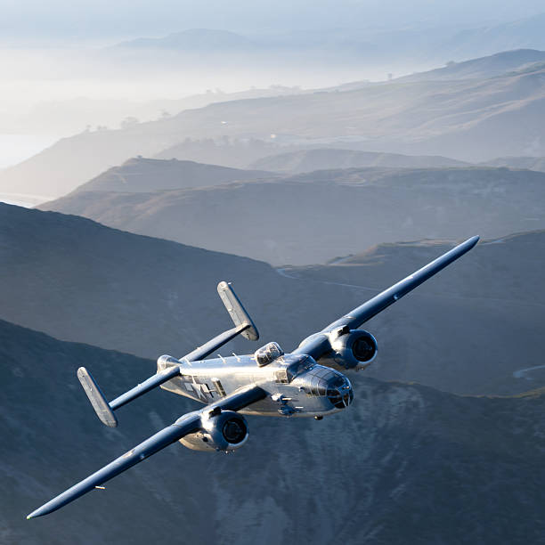 WWII era bomber (B-25 Mitchell)  flying over South California hills