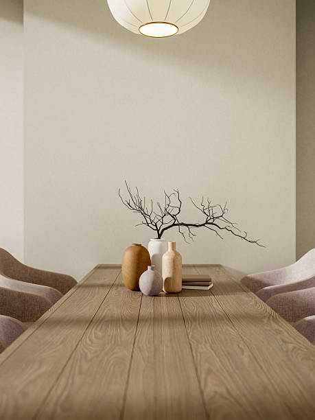 Vases and books on wooden counter table with curve chairs under round hanging lamp in white wall room.