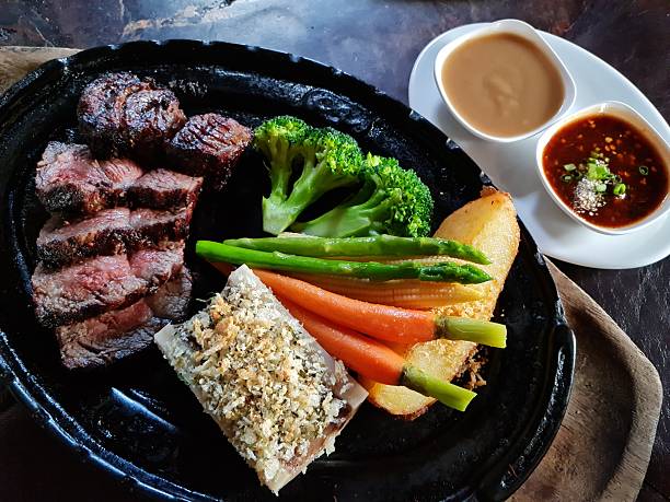 Steak with Vegetables and Dipping Sauces on Hot Plate