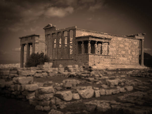 black and white, sepia toned view of the ancient Greek Ionic temple, Erechtheion, on the north side of the Acropolis, featuring the Porch of the Caryatids with six draped female figures, serving as support columns, Athens