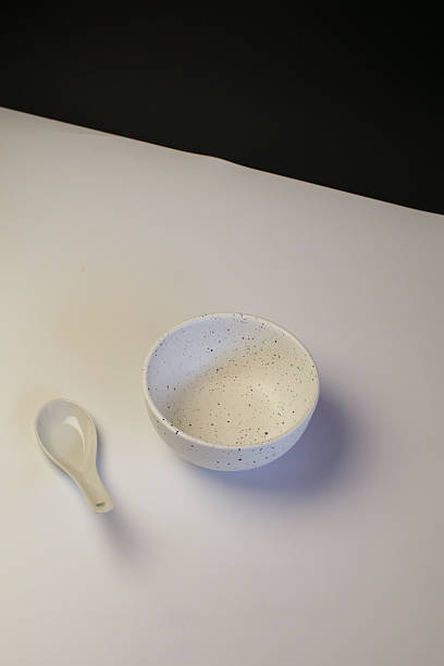 Empty white ceramic bowl with spoon on table with black background. Kitchenware elegant design