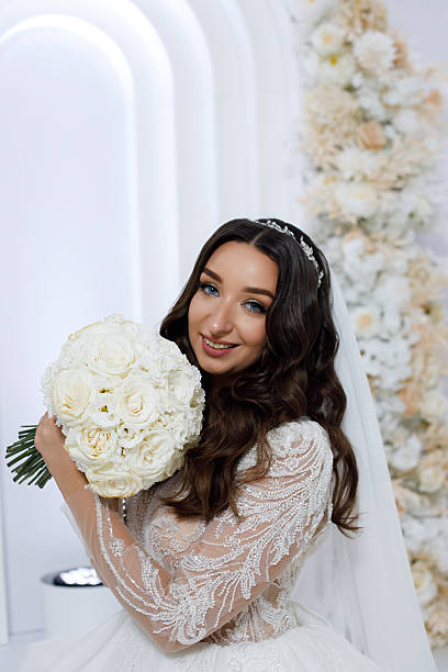 Woman in wedding dress holds bouquet of white flowers in a bright setting during a wedding ceremony in modern venue