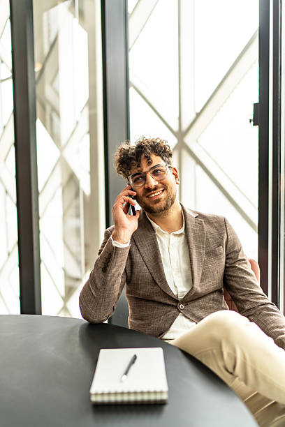 Young man smiling talking on phone in modern office