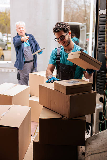 Delivery Workers Coordinating While Unloading Packages From Van