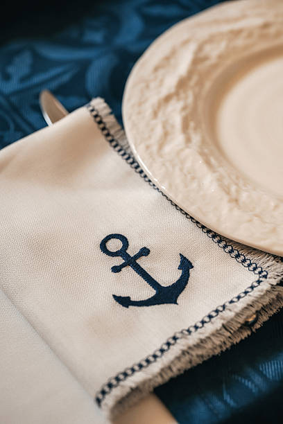 Nautical Table Setting With Anchor Napkin, Closeup Showing Cream Ceramic Plate On Navy Cotton, .