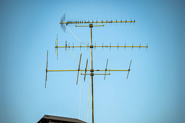 Receiving TV signals from a yagi antenna against a blue sky, connecting homes to broadcast media