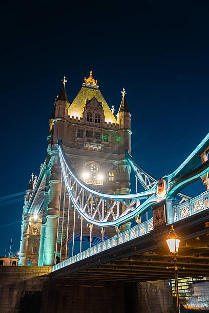 London tower bridge stands illuminated, reflecting its iconic architecture at night