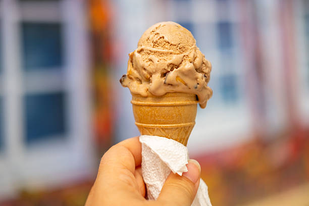 ice cream cone in female hand, woman enjoys double-scoop ice cream cone, capturing summer indulgence, simple pleasures, and joy sweet treats on warm day, happiness in small sweet refreshing moments