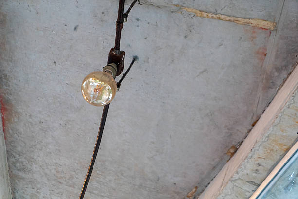 A vintage light bulb hangs from the ceiling, illuminating the space with a warm glow. The exposed wiring adds a retro charm to any interior decor style.