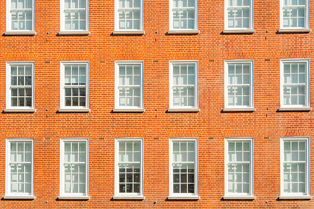 Close up of a london brick building facade with multiple sash windows